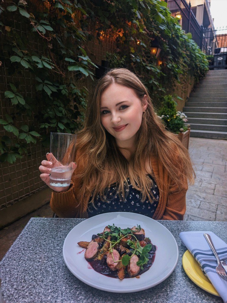 Sarah at an outdoor restaurant holding a glass of water