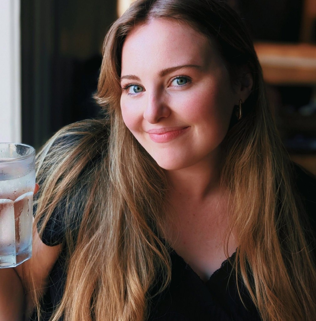 Sarah Kent, smiling and holding a glass of iced water